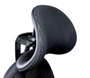 Nahaufnahme der Kopfstütze eines ergonomischen Drehstuhls aus schwarzem Netzstoff, seitliche Perspektive