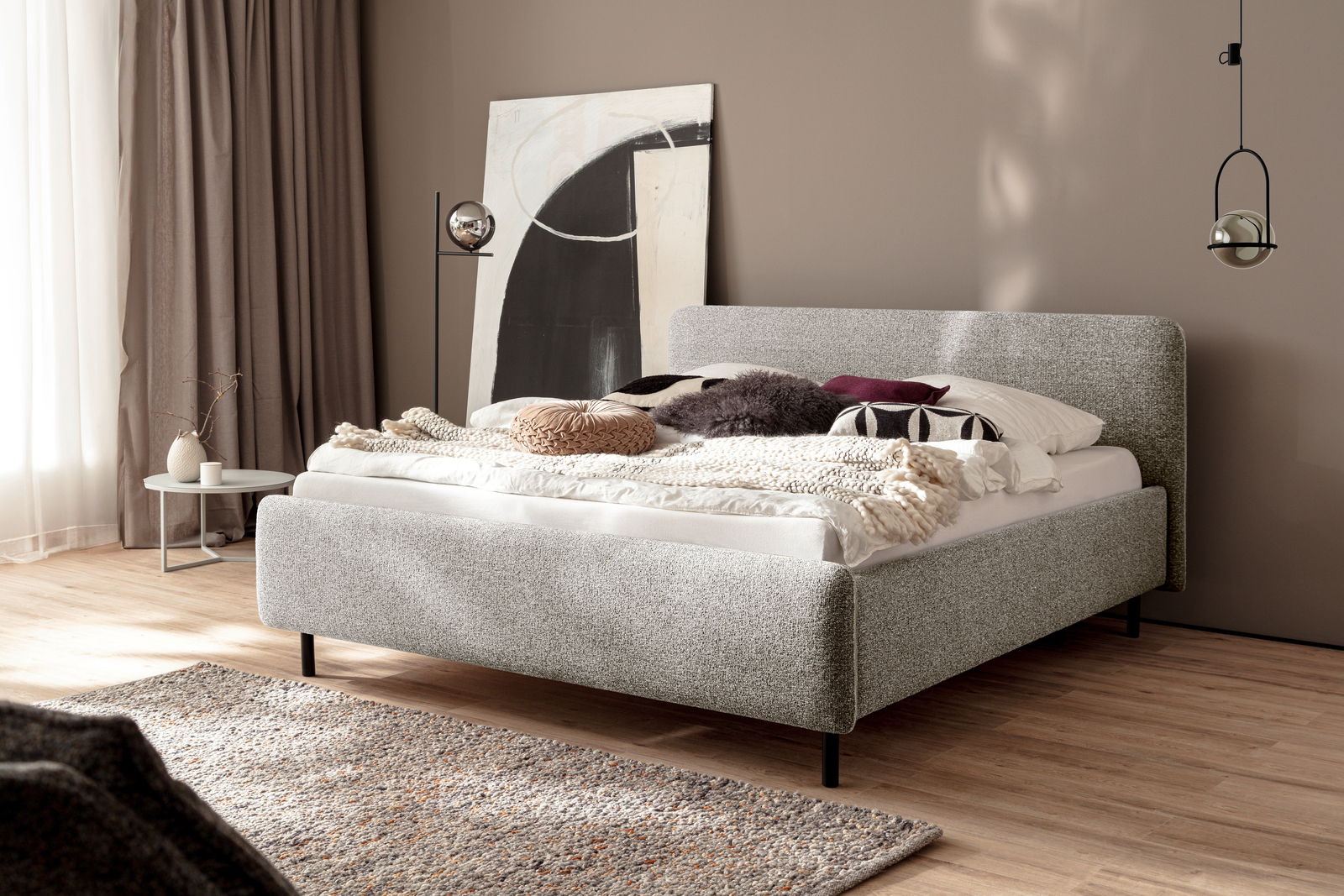 Modernes Polsterbett in einem stilvoll eingerichteten Schlafzimmer, seitliche Perspektive