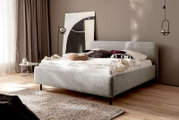 Modern gestoffeerd bed in een stijlvol ingerichte slaapkamer, zijaanzicht