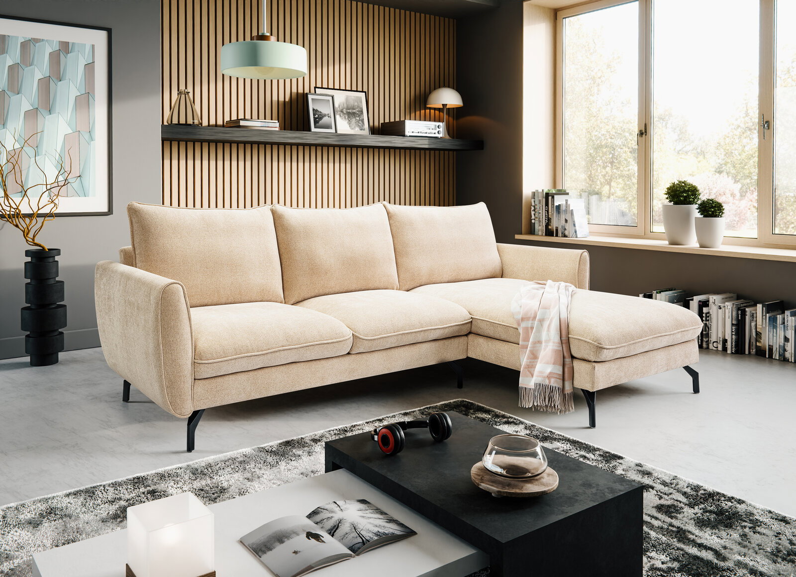 Beiges L-förmiges Ecksofa mit rechter Ottomane und schwarzen Metallfüßen in modernem Wohnzimmer, perspektivisch in schräger Frontansicht von links fotografiert.