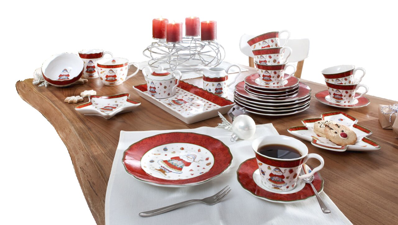 Weihnachtliches Kaffeeservice auf einem festlich gedeckten Tisch mit Kerzen und Weihnachtsbaum im Hintergrund, aus der Vogelperspektive fotografiert.