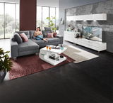 Moderner Couchtisch in Weiß mit zwei Ebenen, dekoriert mit Büchern und Gläsern, in einem stilvollen Wohnzimmer mit grauem Sofa und großen Fenstern, seitliche Perspektive.
