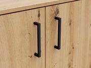 Nahaufnahme einer Kommode aus hellem Holz mit zwei schwarzen, modernen Griffen. Perspektive von vorne.