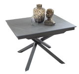 Moderner Esstisch TOKYO mit grauer Tischplatte und gekreuztem Metallgestell, dekoriert mit Vasen und einer Skulptur, seitliche Perspektive.