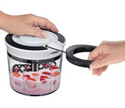 Multischneider Turbo in der Seitenansicht, mit einer Hand, die den Deckel hält, und einer anderen Hand, die an der Zugleine zieht, um Erdbeeren in Joghurt zu zerkleinern.