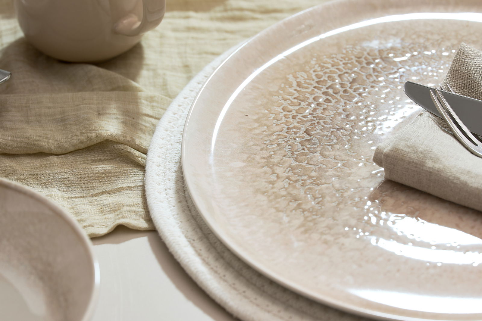 Nahaufnahme eines Tellers mit elegantem Muster, auf einem Tisch mit Besteck und Stoffserviette arrangiert.
