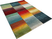 Bunter Teppich im Patchwork-Design mit farbigen Quadraten in Rot, Blau, Grün, Gelb und Grau, schräg von oben in Perspektive fotografiert