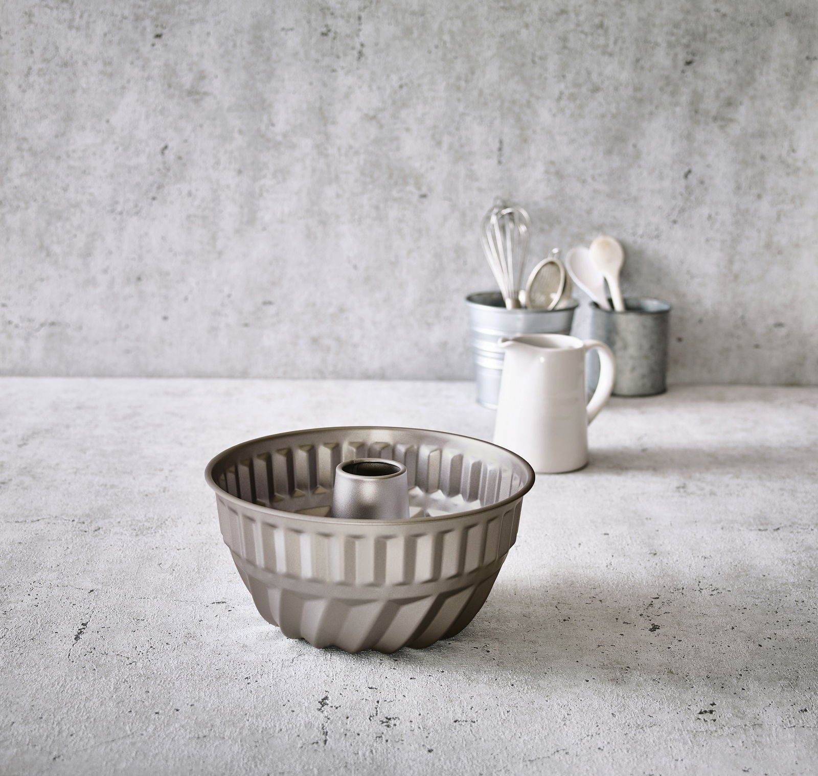 Birkmann Gugelhupfform BASIC BAKING Gugelhupfform aus Metall, seitliche Perspektive, auf einer Küchenarbeitsplatte mit Küchenutensilien im Hintergrund.