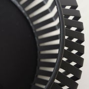 Nahaufnahme einer schwarzen Schale mit modernem, geometrischem Design und offenen Streben, seitliche Perspektive.