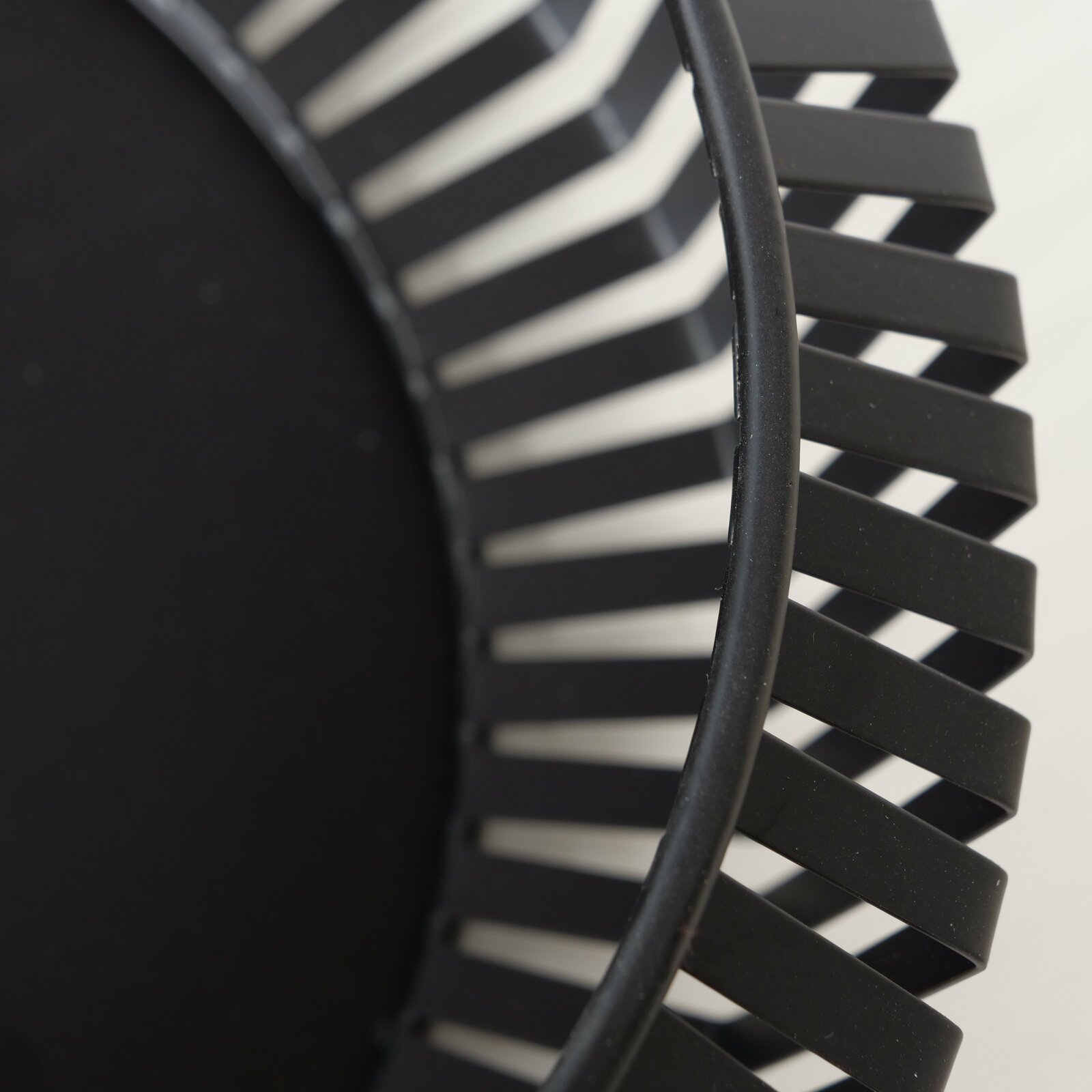 Nahaufnahme einer schwarzen Schale mit modernem, geometrischem Design und offenen Streben, seitliche Perspektive.