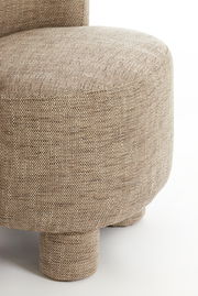 Nahaufnahme eines Sessels mit beigem Stoffbezug und runden Beinen, seitliche Perspektive.