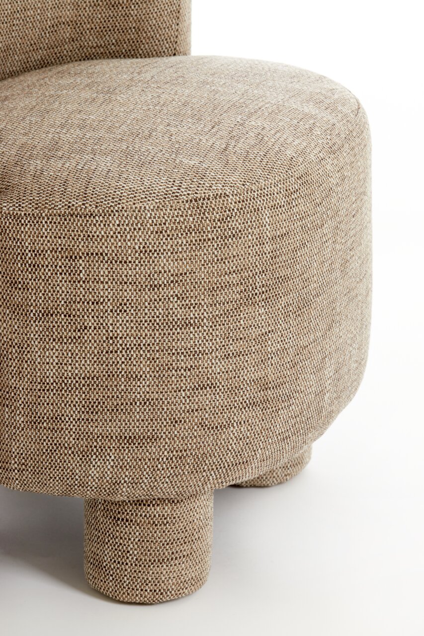 Close-up van een fauteuil met een beige stoffen bekleding en ronde poten, gezien vanaf de zijkant.