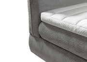 Nahaufnahme eines grauen Boxspringbetts mit gestepptem weißen Topper, seitliche Perspektive