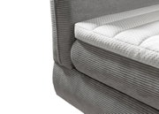 Close-up van een grijs boxspringbed met een gewatteerde witte topper, gezien vanaf de zijkant