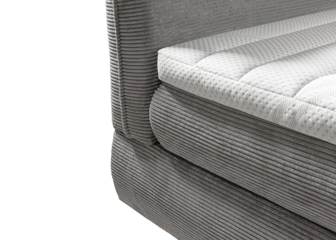 Close-up van een grijs boxspringbed met een gewatteerde witte topper, gezien vanaf de zijkant
