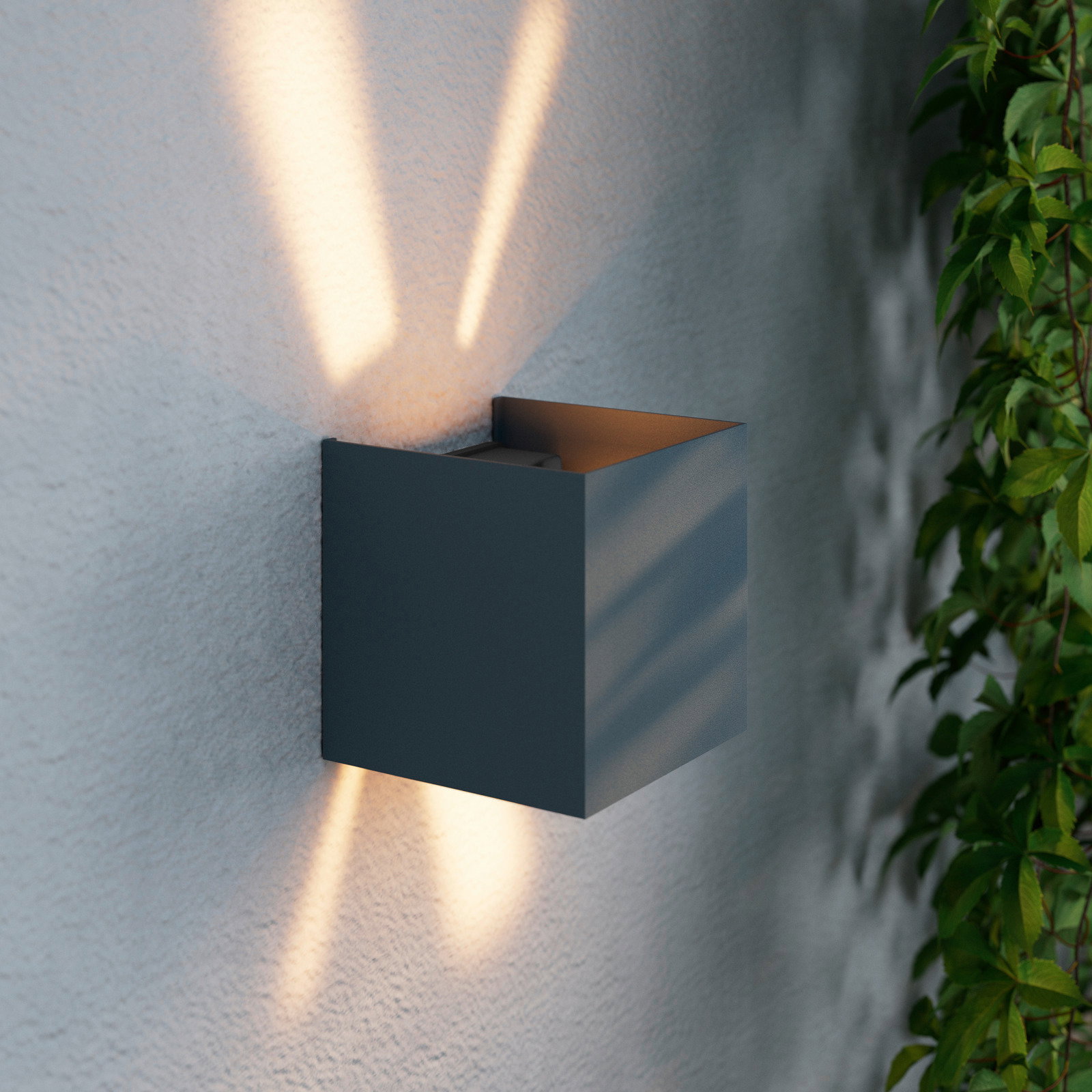 Moderne LED-Wandleuchte in kubischer Form, die warmes Licht nach oben und unten an eine Wand abstrahlt, seitliche Perspektive.