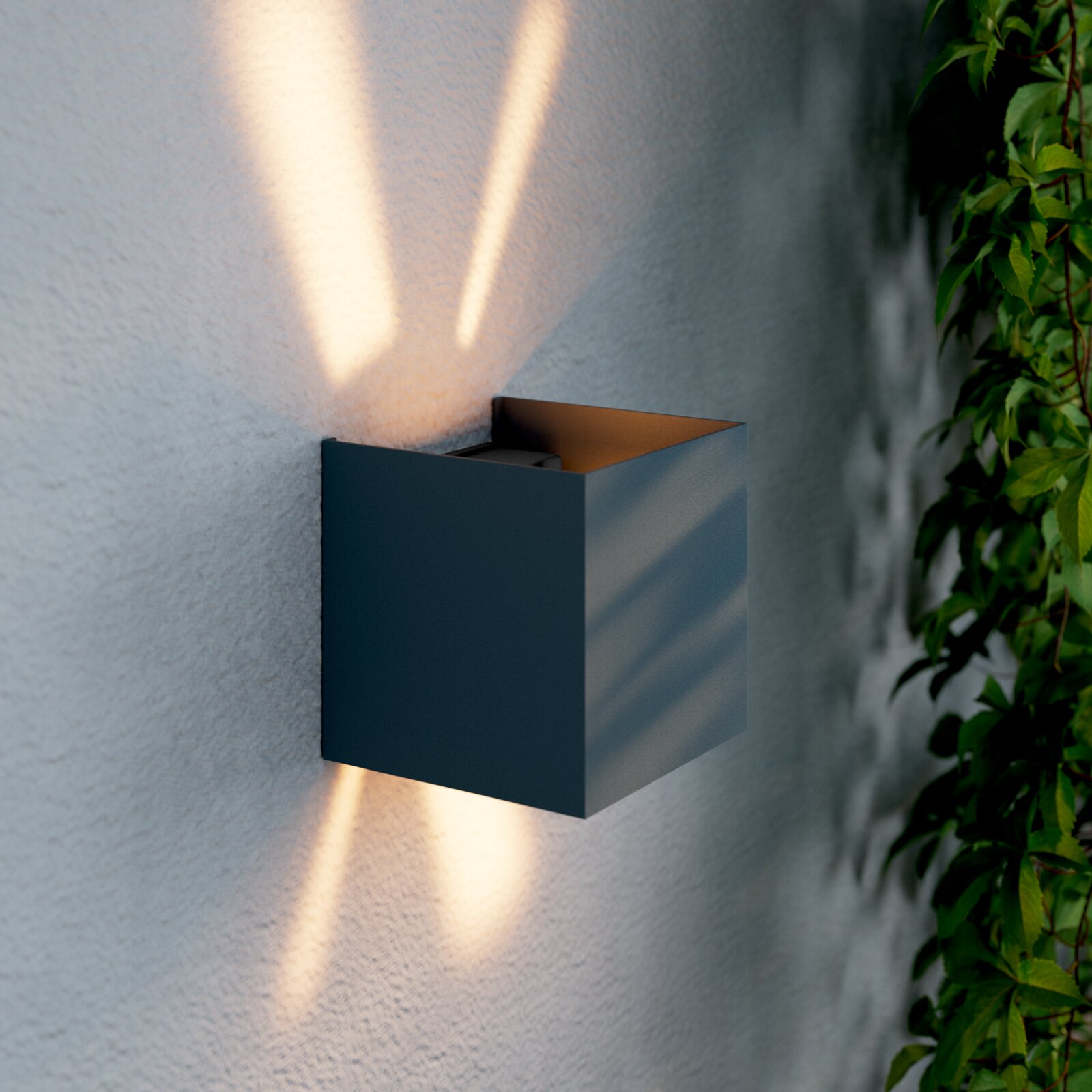 Novel LED-Wandleuchte WANDLEUCHTE Moderne LED-Wandleuchte in kubischer Form, die warmes Licht nach oben und unten an eine Wand abstrahlt, seitliche Perspektive.