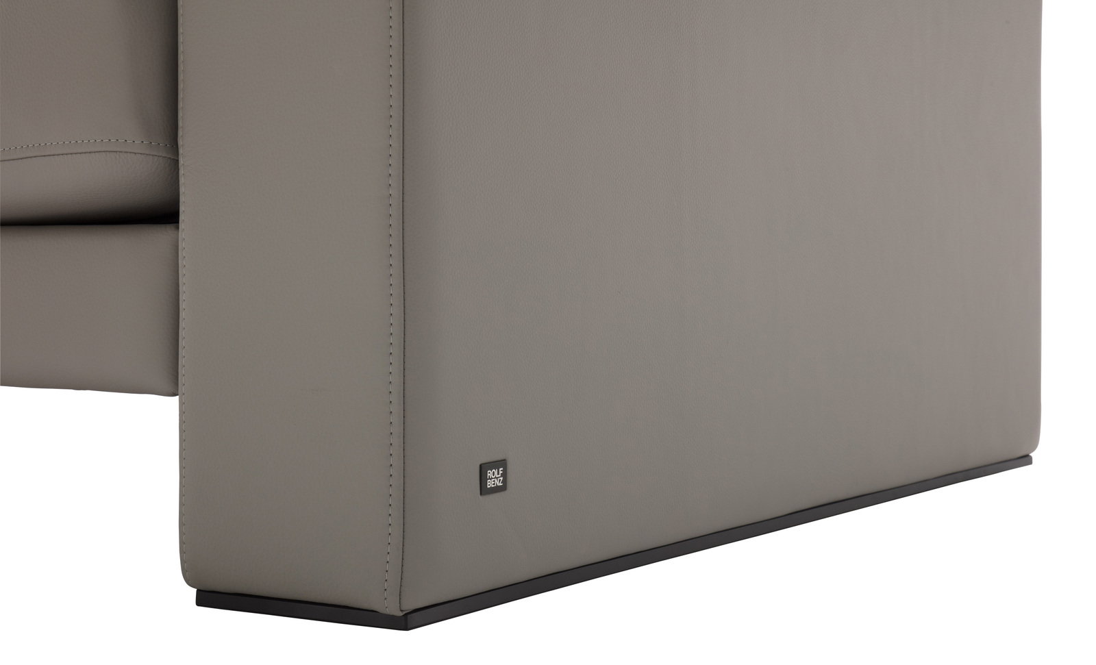 Nahaufnahme der Seitenansicht einer grauen Sofabank mit einem kleinen Logo auf der unteren Ecke.