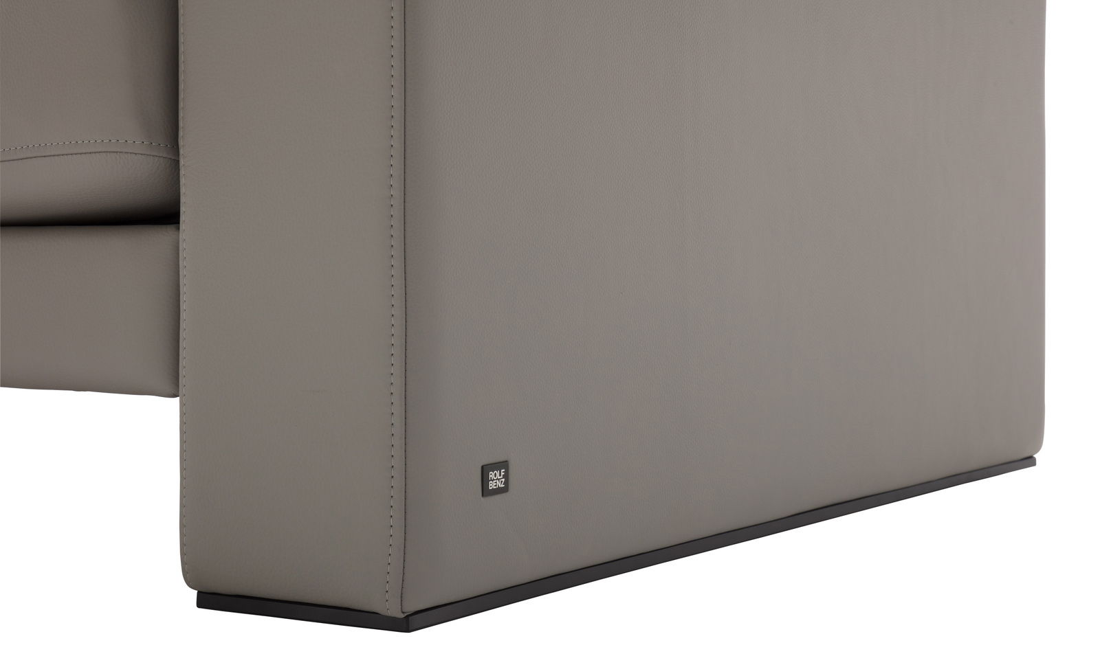 Nahaufnahme der Seitenansicht einer grauen Sofabank mit einem kleinen Logo auf der unteren Ecke.