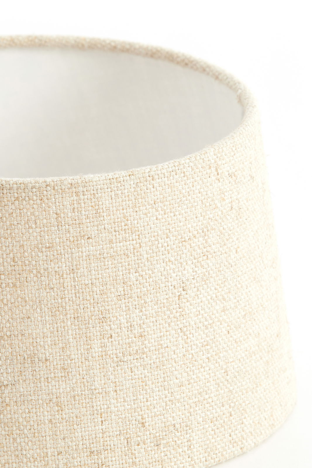 Nahaufnahme eines runden, cremefarbenen Lampenschirms aus grobem Stoff, seitliche Perspektive.
