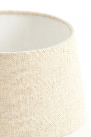 Nahaufnahme eines runden, cremefarbenen Lampenschirms aus grobem Stoff, seitliche Perspektive.