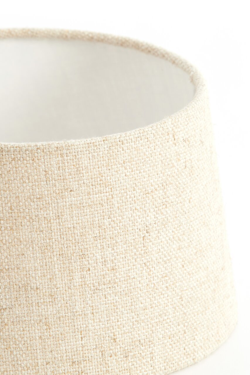 Nahaufnahme eines runden, cremefarbenen Lampenschirms aus grobem Stoff, seitliche Perspektive.