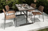 Vier Stapelsessel aus Rattan mit Metallrahmen um einen modernen Gartentisch, Perspektive von schräg oben.