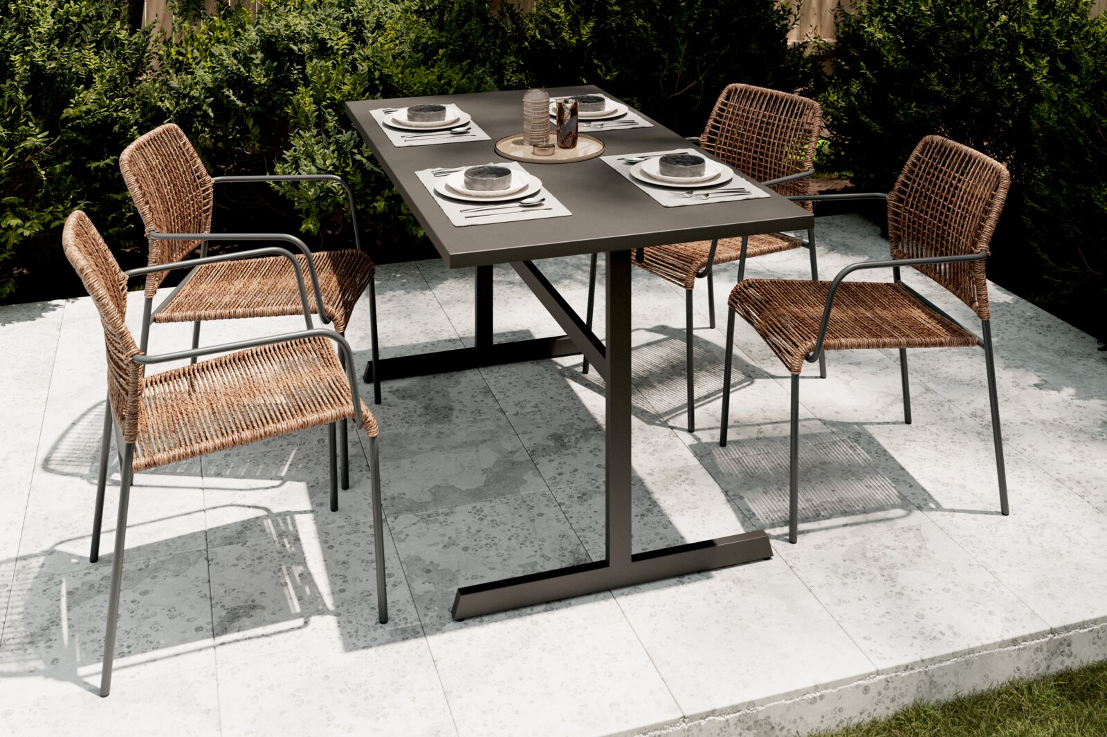 Vier Stapelsessel aus Rattan mit Metallrahmen um einen modernen Gartentisch, Perspektive von schräg oben.