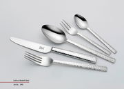 Set aus glänzendem Besteck mit gehämmerten Griffen, bestehend aus Messer, Gabel, Löffel und Teelöffel, in schräger Draufsicht.