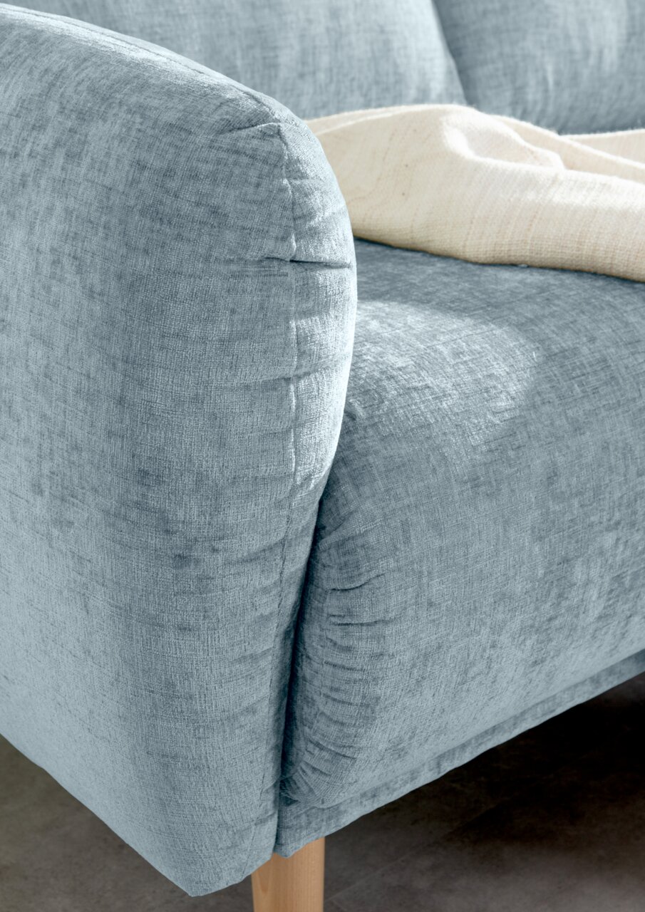 Nahaufnahme einer hellblauen Sofaecke mit Holzbeinen, von der Seite betrachtet.