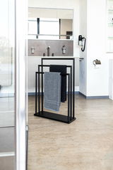 Moderner schwarzer Handtuchständer mit zwei Handtüchern in einem stilvollen Badezimmer, seitliche Perspektive.