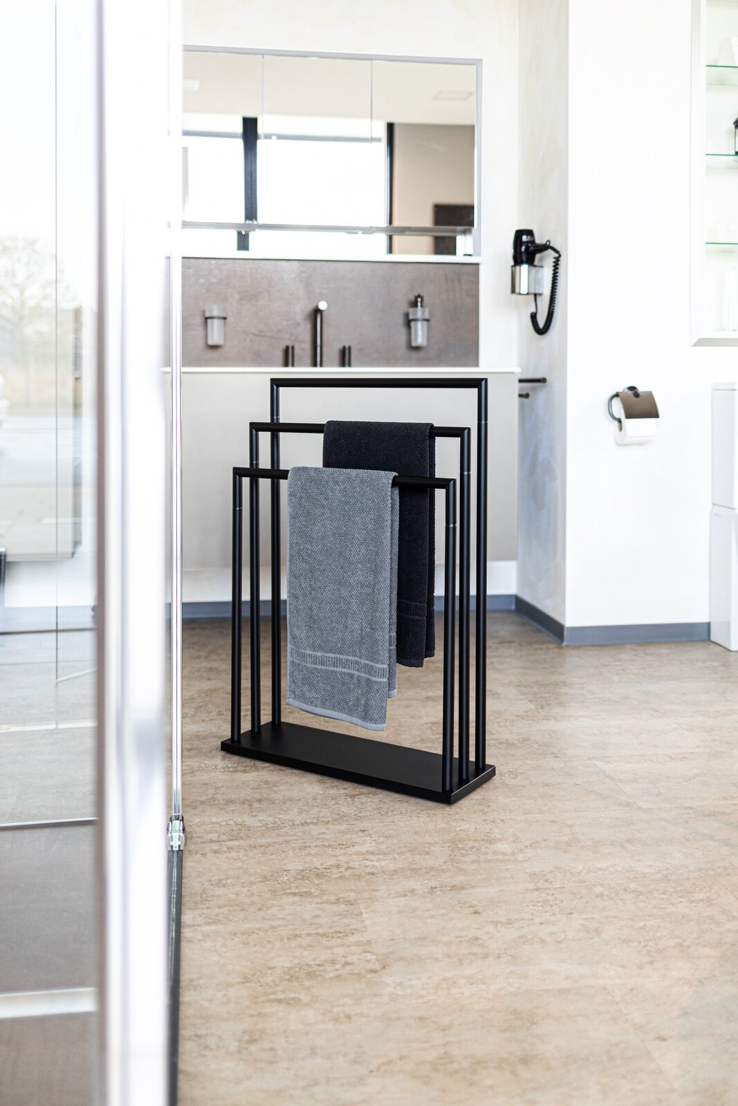 Moderner schwarzer Handtuchständer mit zwei Handtüchern in einem stilvollen Badezimmer, seitliche Perspektive.