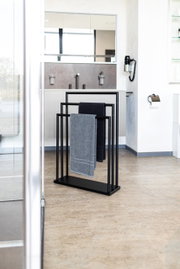 Moderne zwarte handdoekhouder met twee handdoeken in een stijlvolle badkamer, gezien vanaf de zijkant.