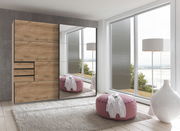 Moderner Schwebetürenschrank mit Holzoptik und Spiegelfront, seitliche Perspektive im hellen Raum mit großen Fenstern.