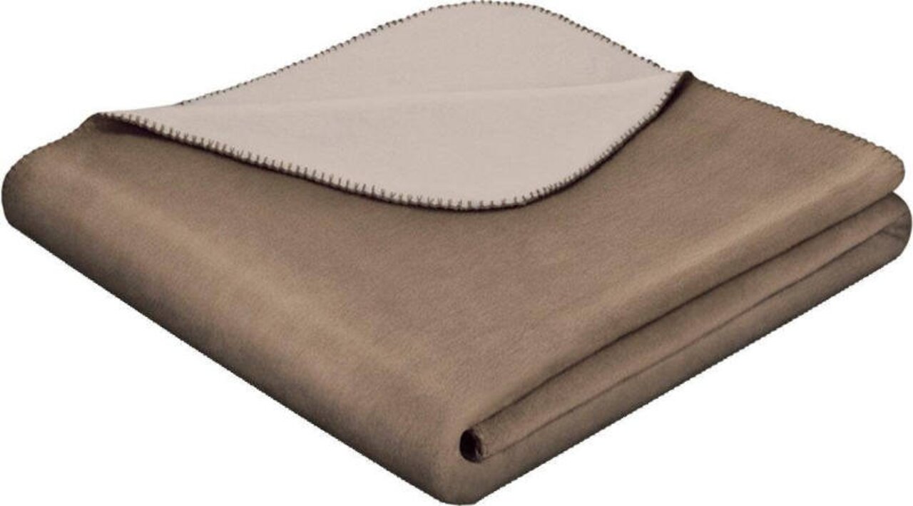 Gefaltete zweifarbige Wohndecke in Braun und Beige, von schräg oben fotografiert.