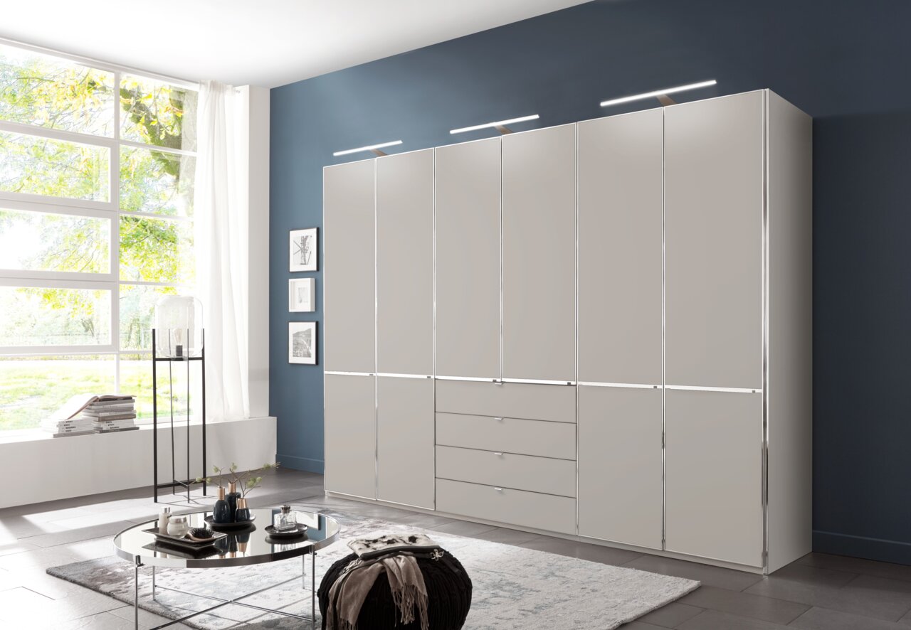 Moderner Funktionsschrank in einem stilvollen Wohnzimmer, frontal betrachtet, mit mehreren Türen und Schubladen, beleuchtet von eleganten Leuchten.