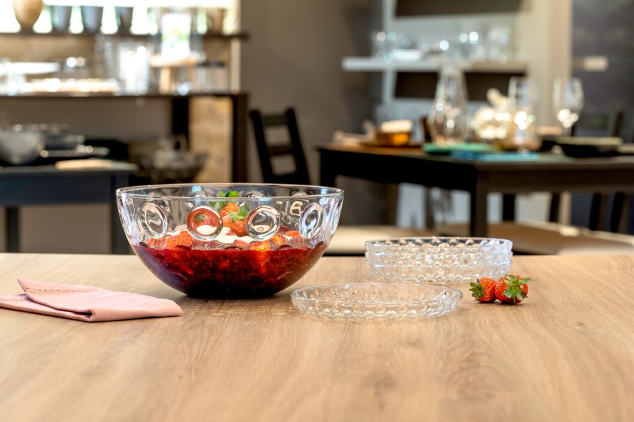 Leonardo Teller CUCINA Glas-Schüssel mit optischem Design, gefüllt mit roten Früchten, auf einem Tisch in einem Esszimmer, seitliche Perspektive