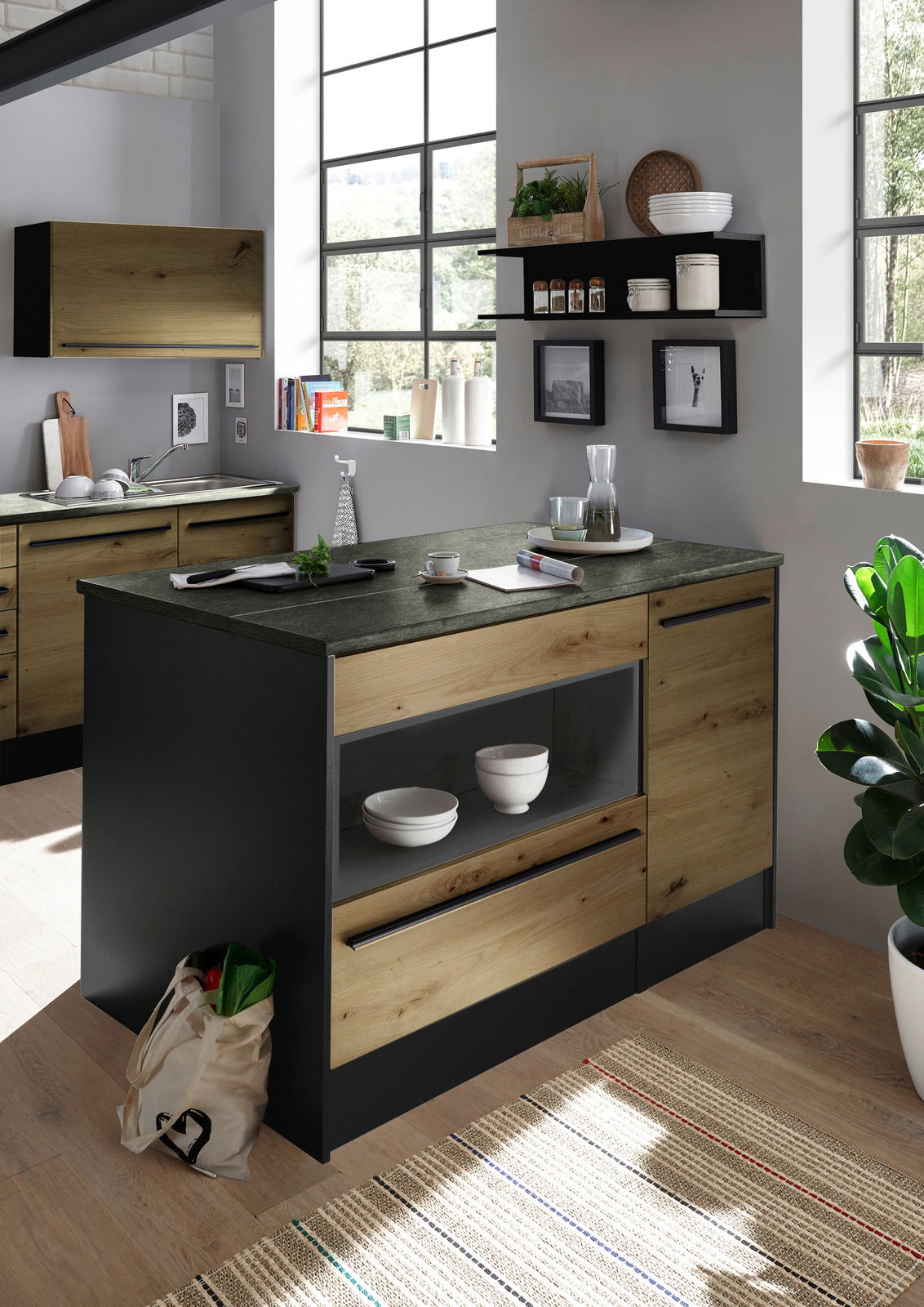 Moderne Kücheninsel aus Holz und dunklem Material, mit Regalen und Schubladen, in einer hellen Küche mit großen Fenstern, seitliche Perspektive.