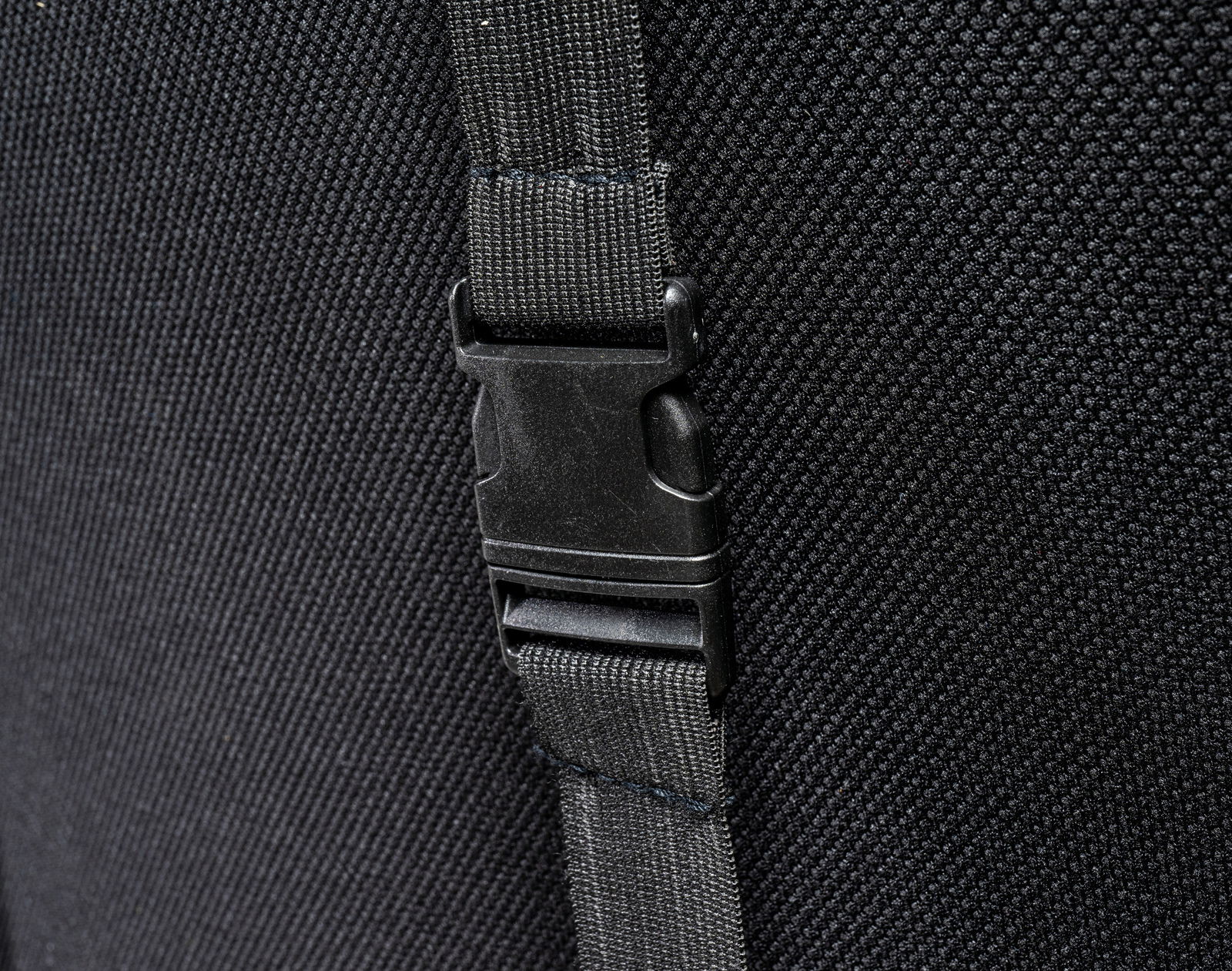 Nahaufnahme eines schwarzen Gurts mit Schnalle an einem Gaming Stuhl, seitliche Perspektive