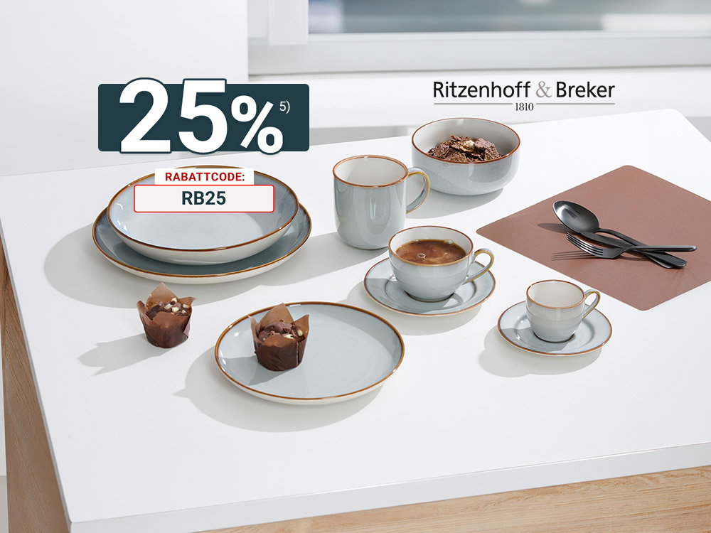 Graues Keramik-Geschirr mit Tassen, Schalen und Tellern auf weißem Tisch, dazu Kaffee und Muffins.