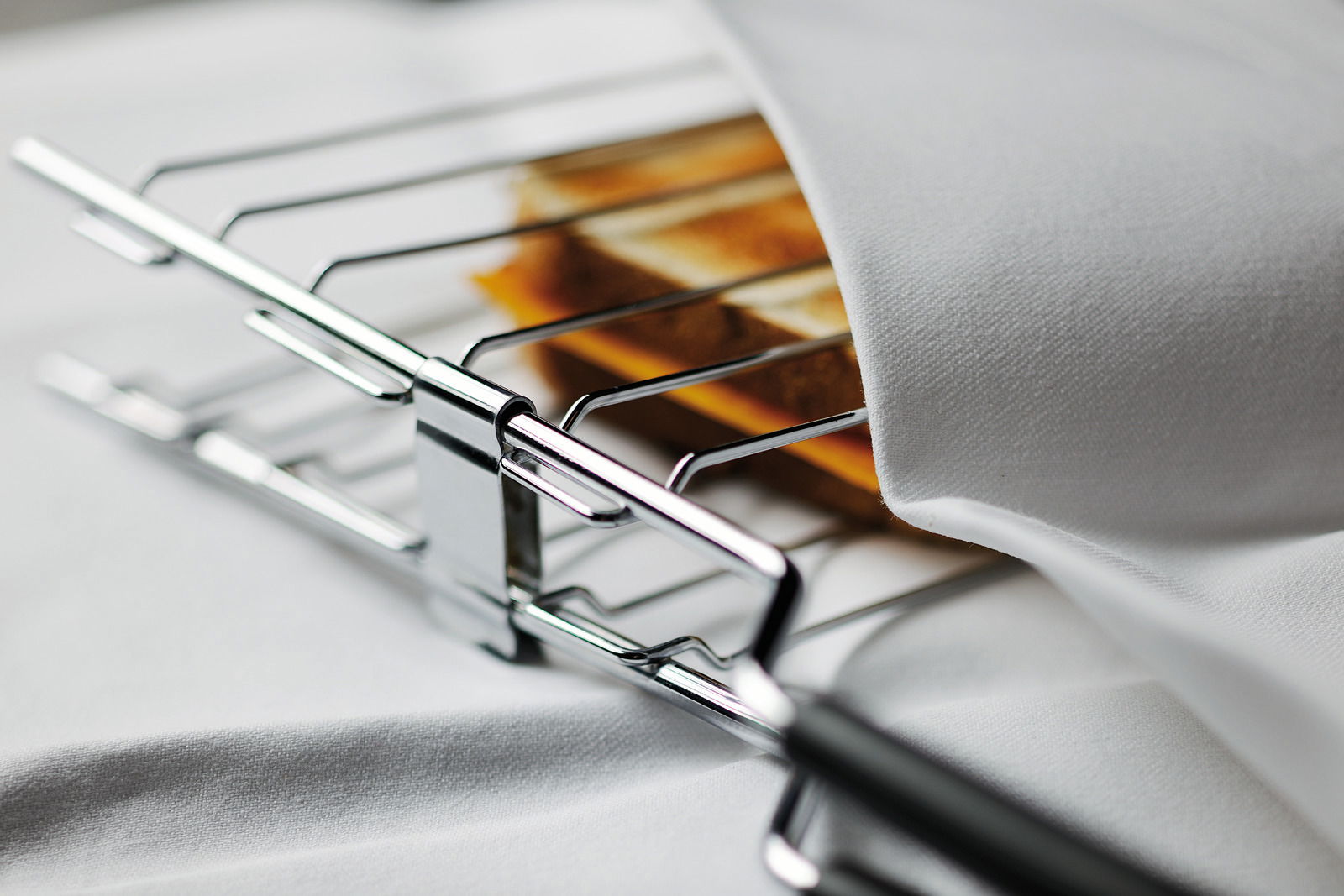 Nahaufnahme eines Toasters mit zwei Scheiben Toastbrot, teilweise von einem weißen Tuch bedeckt.