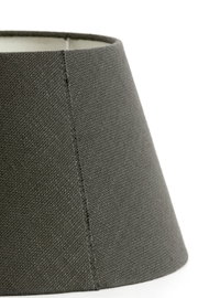 Close-up van een ronde, grijze stoffen lampenkap, gezien vanaf de zijkant