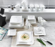 Vogelperspektive auf ein 42-teiliges Kombiservice-Set 'Melodie' mit weißen Tellern, Tassen und Schalen auf einem Tisch arrangiert.