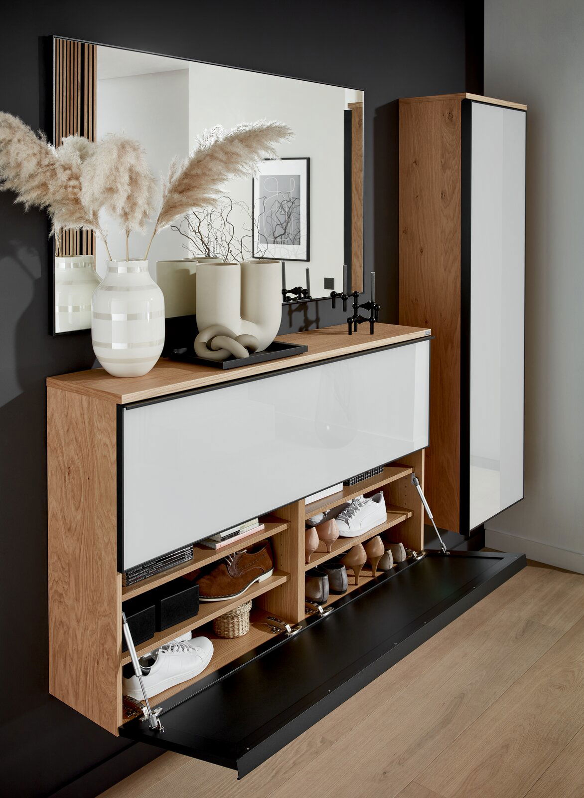 Garderoben-Set mit Holz- und Weißelementen, bestehend aus einem großen Spiegel, einem Schuhschrank mit Klapptüren und einem hohen Schrank. Dekoriert mit Vasen und Kerzenhaltern, seitliche Perspektive.