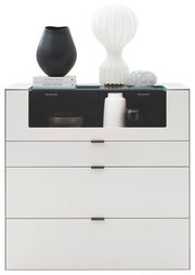 Frontale Ansicht eines modernen weißen Highboards mit drei Schubladen und einer Glasablage, dekoriert mit Vasen und Büchern.
