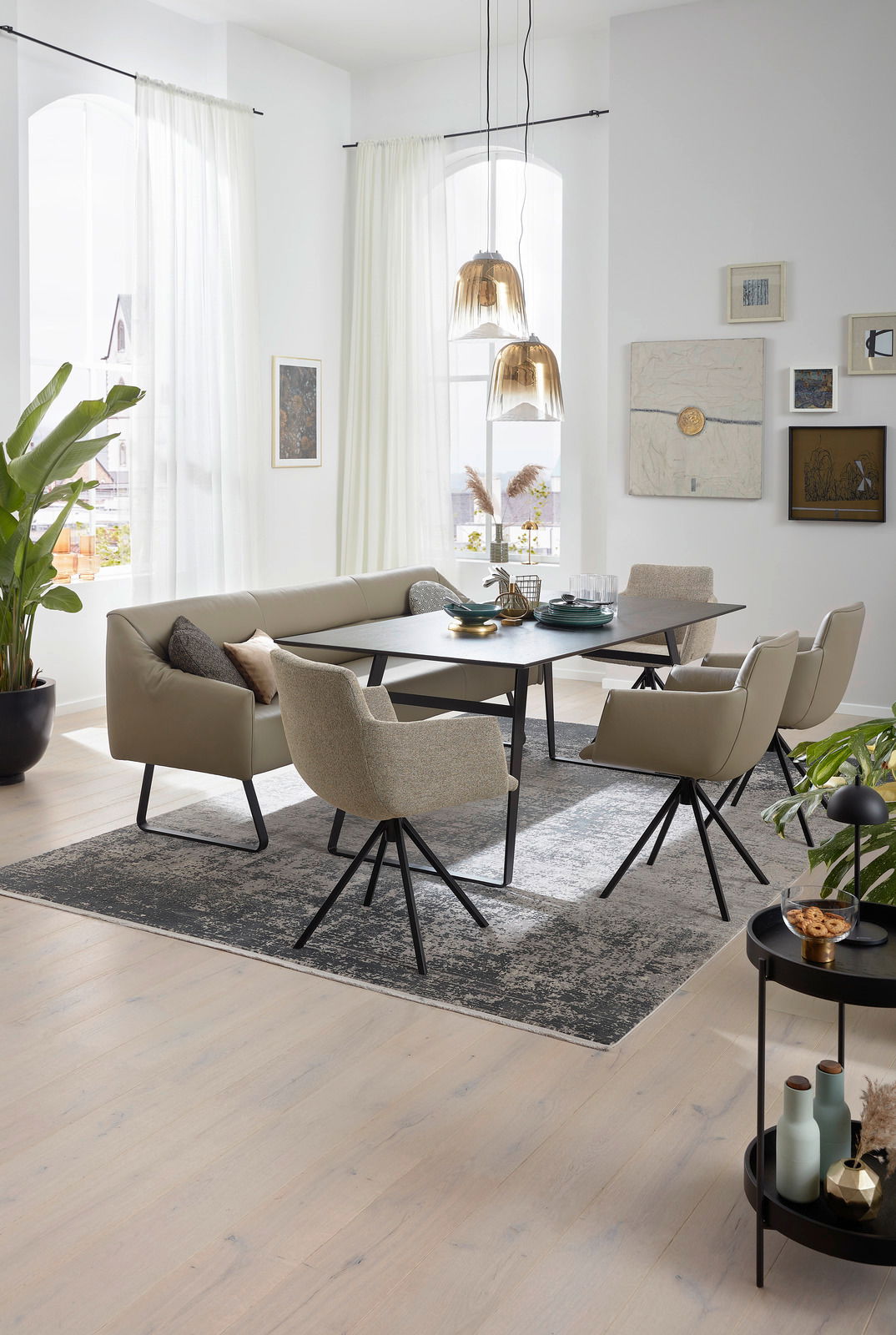 Moderner Esstisch mit schwarzer Tischplatte und beige gepolsterten Stühlen in einem hellen, stilvollen Esszimmer. Perspektive von schräg oben.