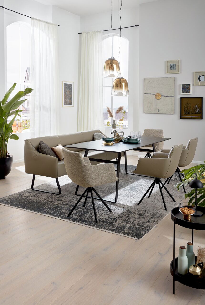 Moderner Esstisch mit schwarzer Tischplatte und beige gepolsterten Stühlen in einem hellen, stilvollen Esszimmer. Perspektive von schräg oben.