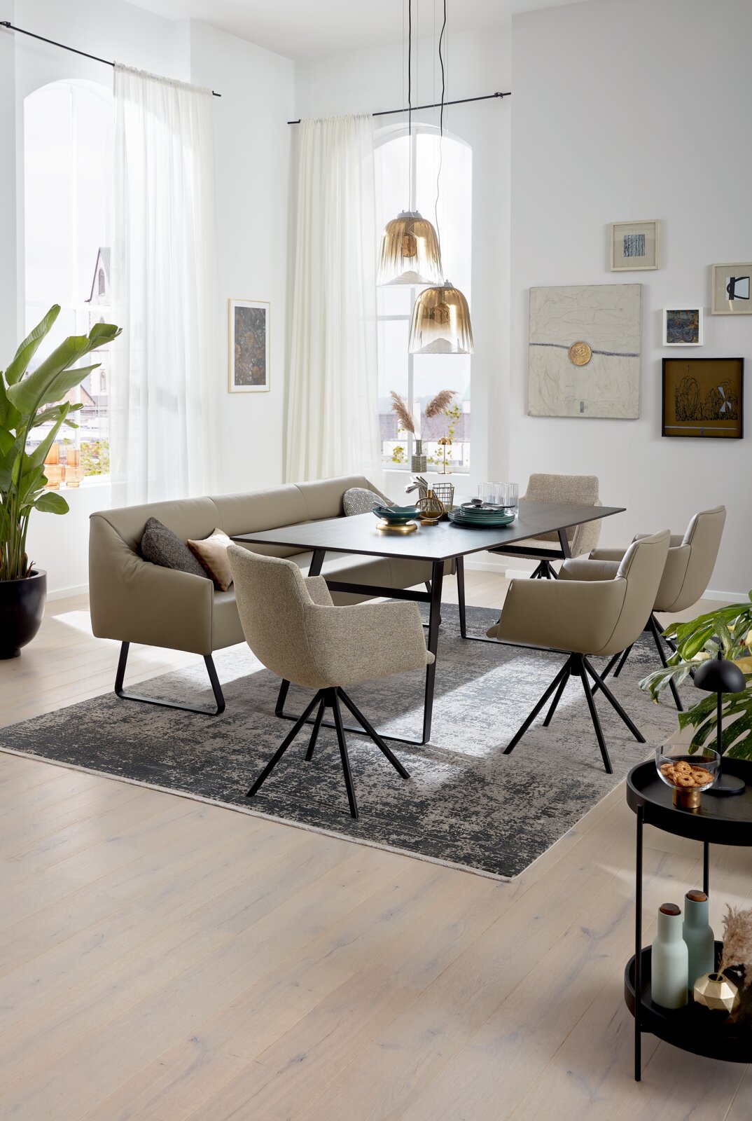 Moderner Esstisch mit schwarzer Tischplatte und beige gepolsterten Stühlen in einem hellen, stilvollen Esszimmer. Perspektive von schräg oben.