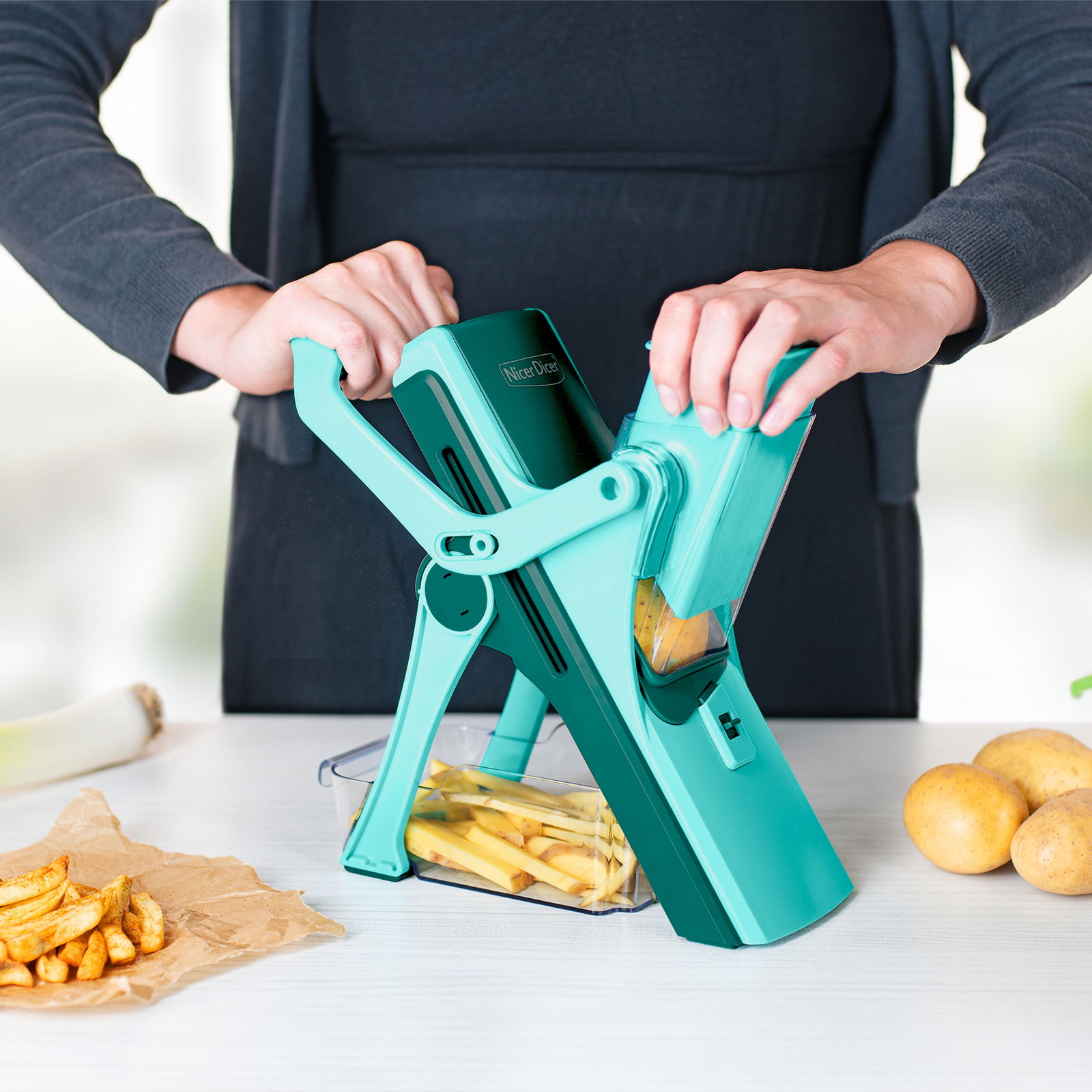 Person benutzt den Nicer Dicer Mando, Set 10-tlg., um Kartoffeln in Pommes zu schneiden. Perspektive von vorne.