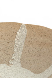Nahaufnahme eines Ornaments mit bräunlicher, gesprenkelter Oberfläche und einem weißen, rissigen Muster. Perspektive von oben.